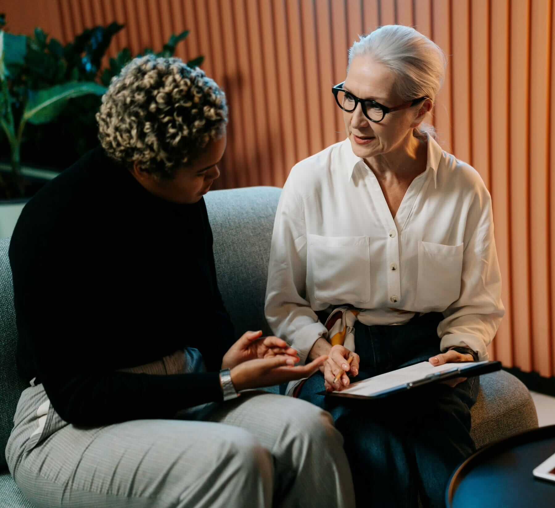 two women discussing paperwork on clipboard