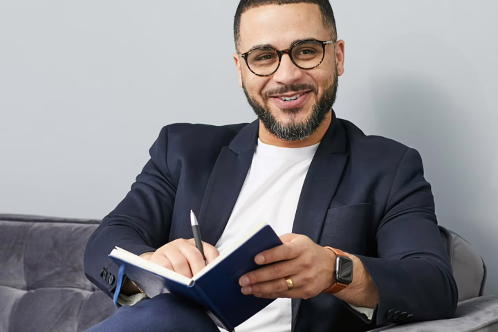 smiling business man sitting on couch with notebook and pen