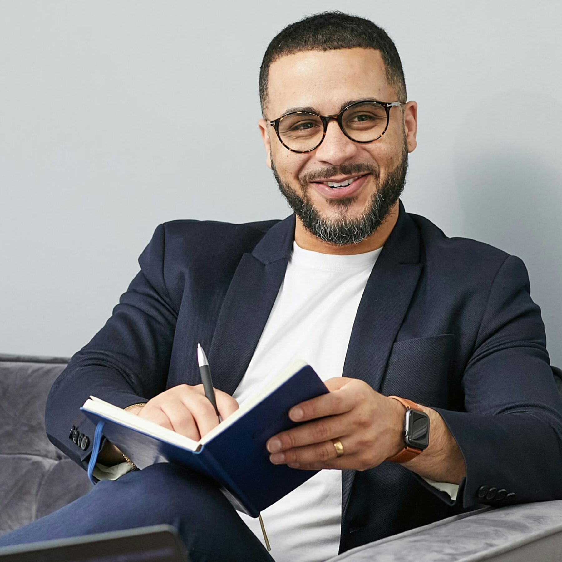 smiling business man sitting on couch with notebook and pen
