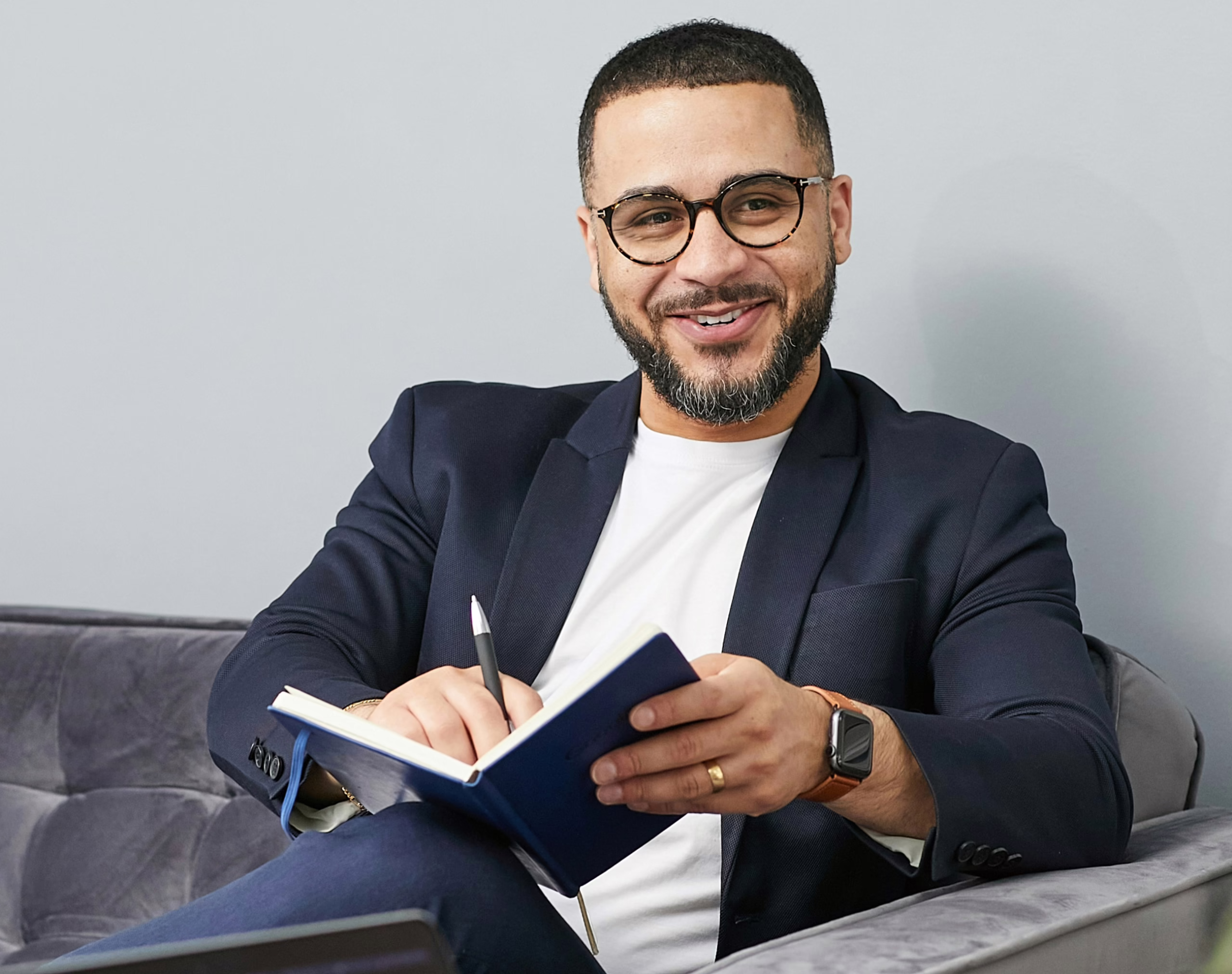 smiling business man sitting on couch with notebook and pen