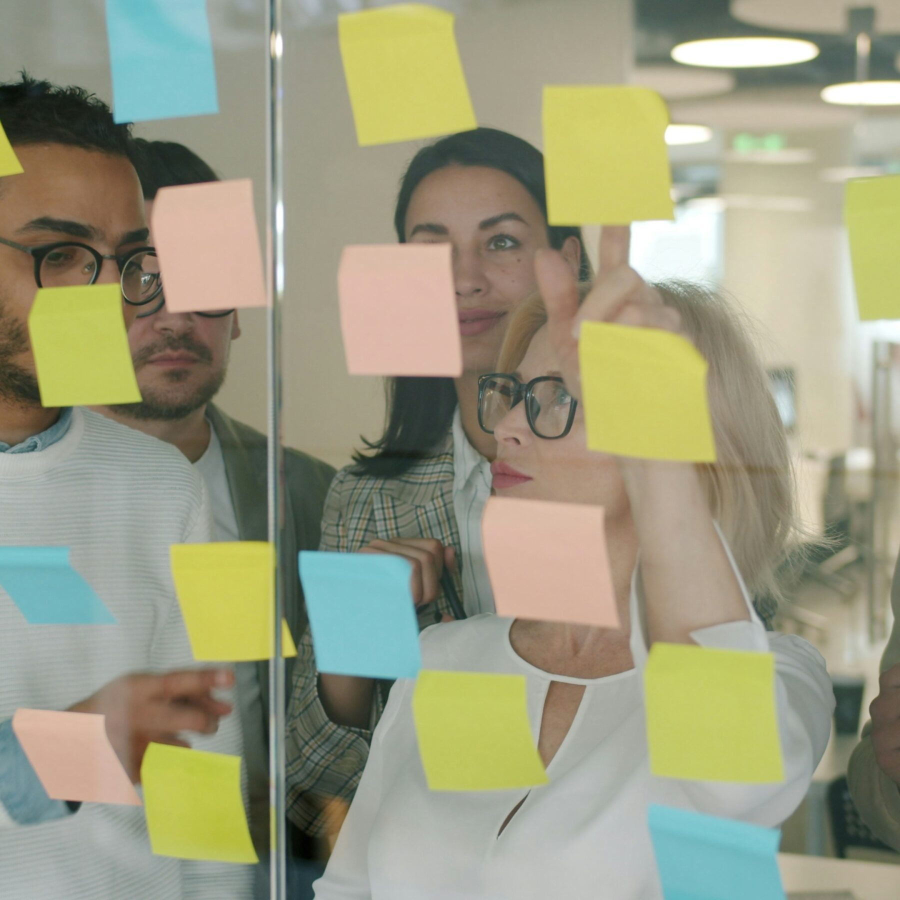 marketing team reviewing post it notes on glass wall