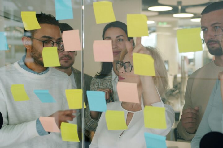 marketing team reviewing post it notes on glass wall