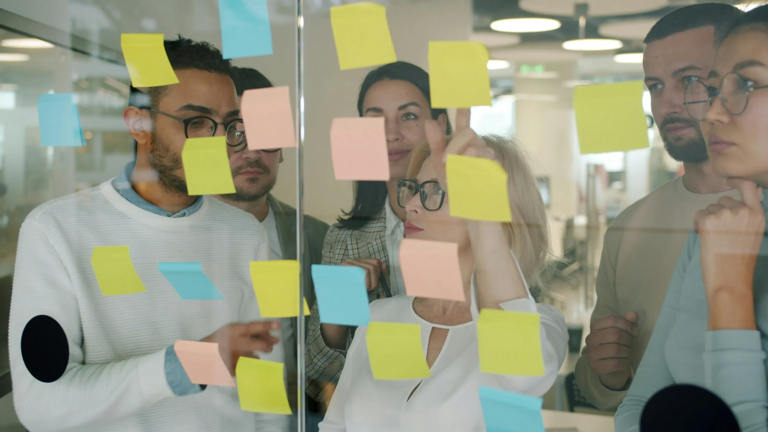 marketing team reviewing post it notes on glass wall