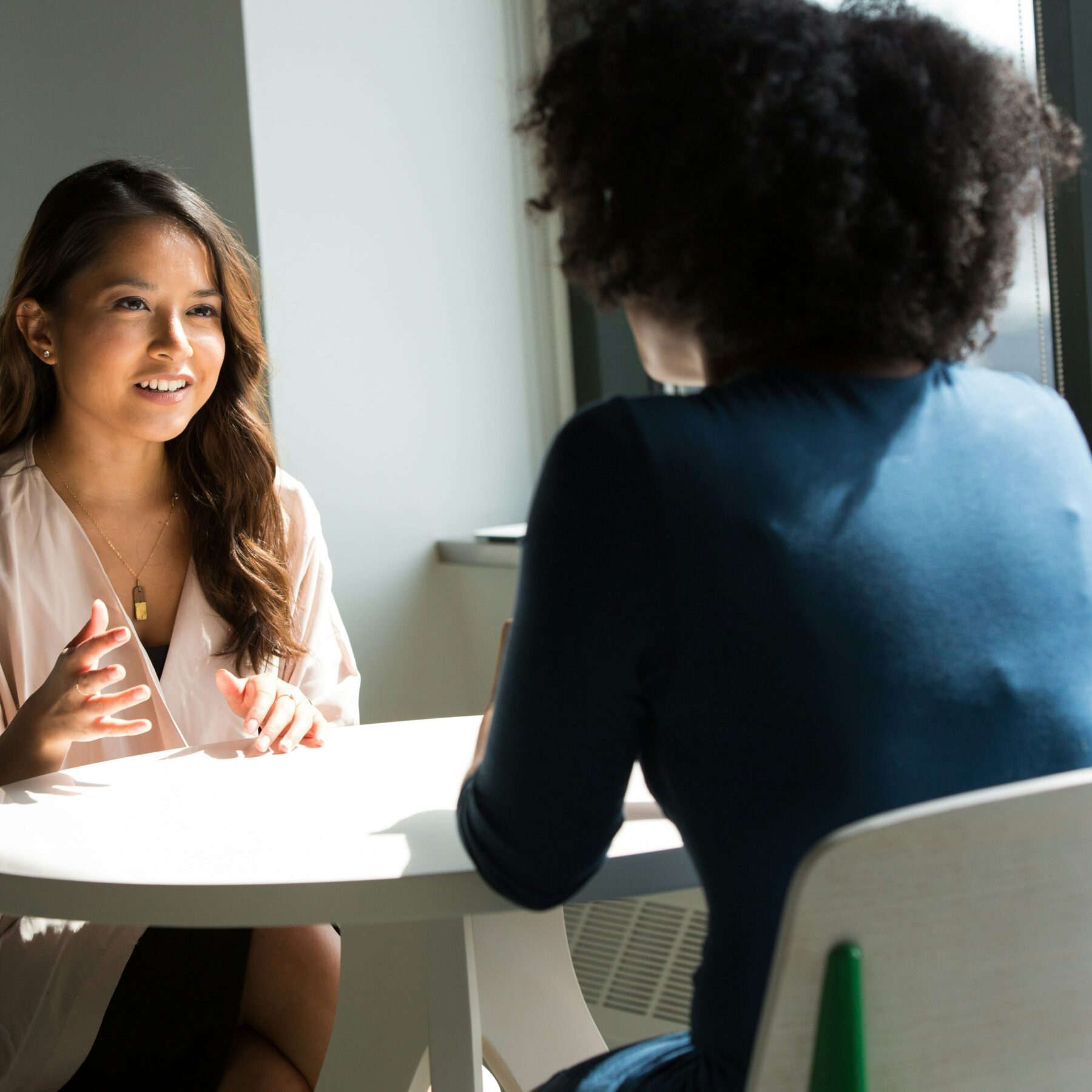 two businesswomen talking at a small white table