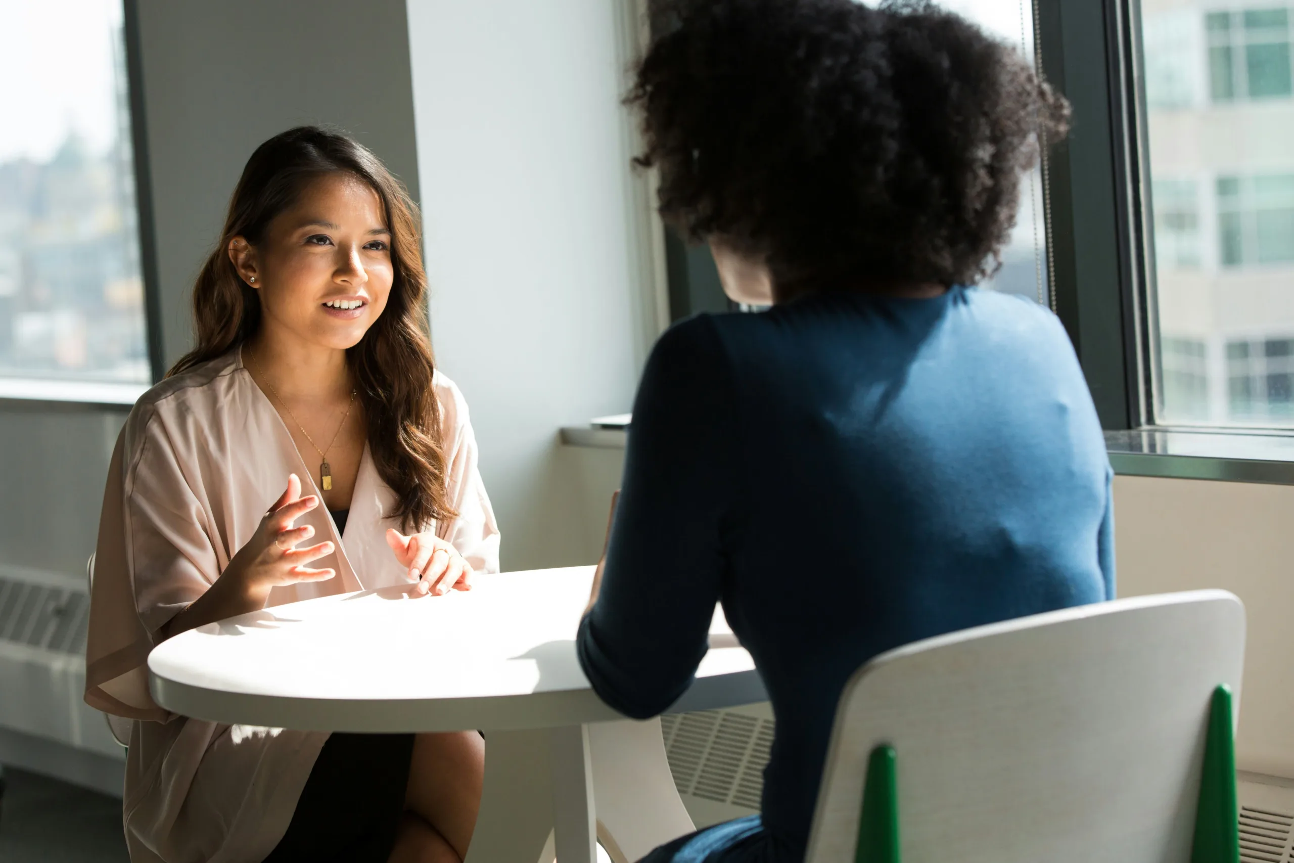 two businesswomen talking at a small white table