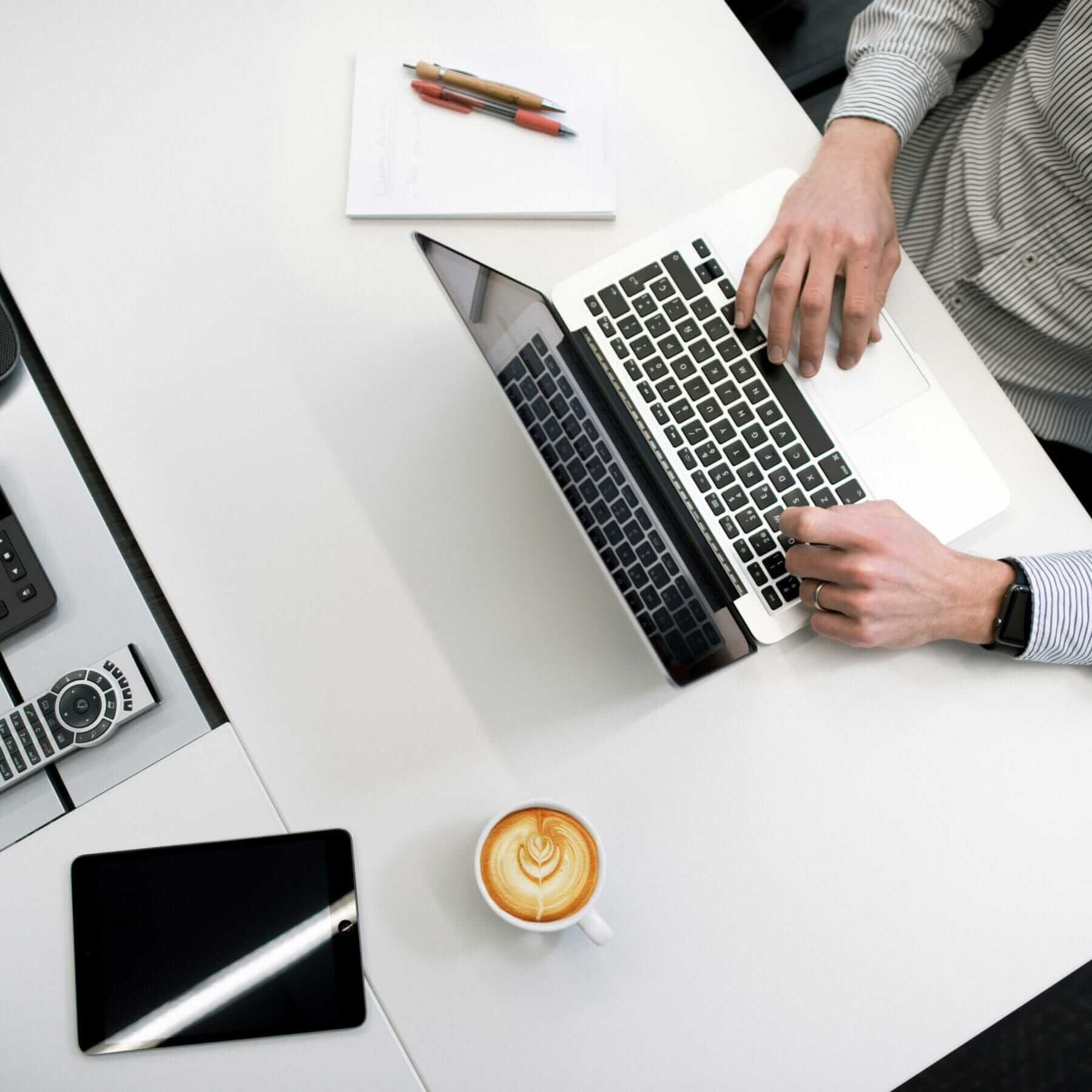 person using laptop on a desk with coffee nearby