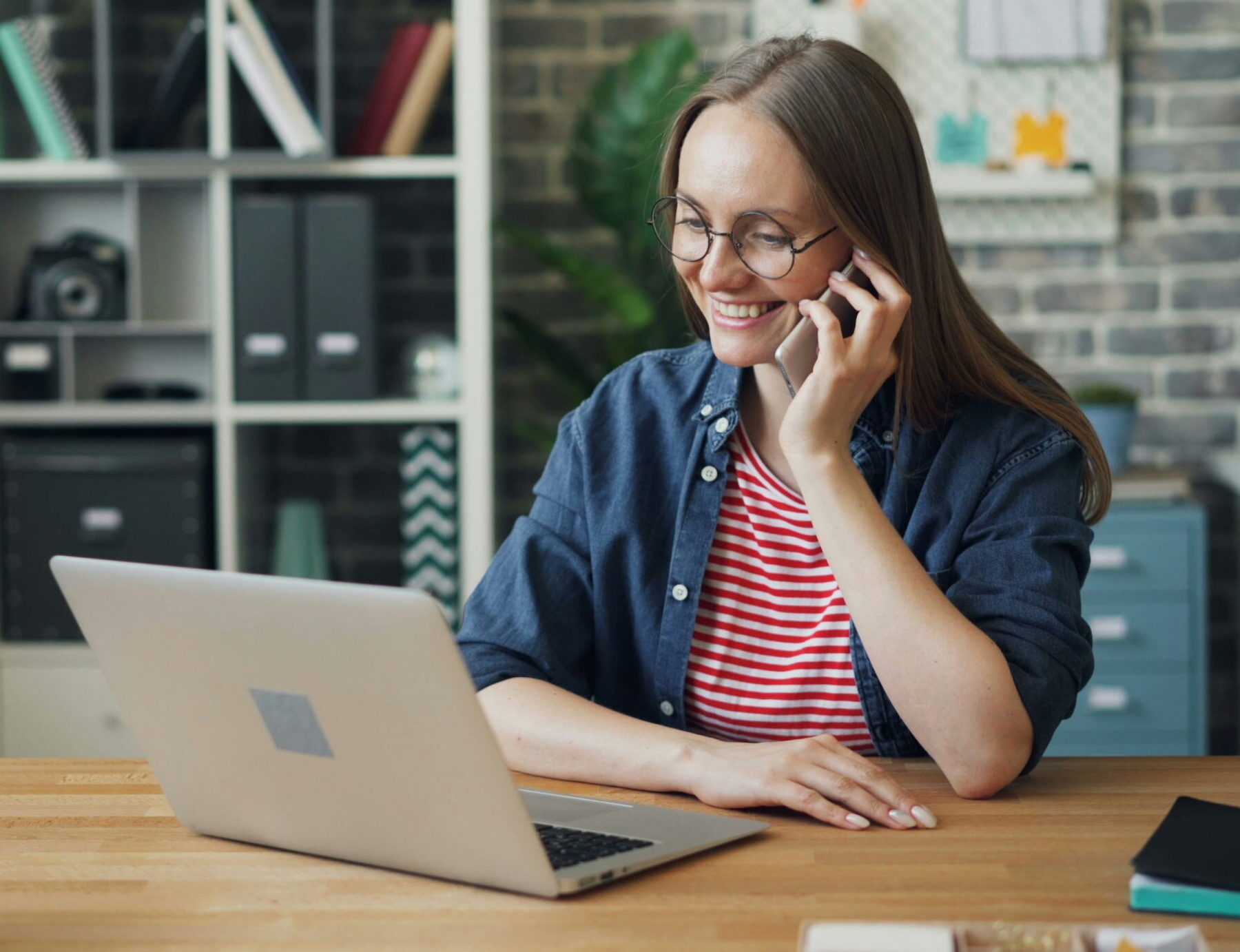 woman talking on phone in front of laptop computer