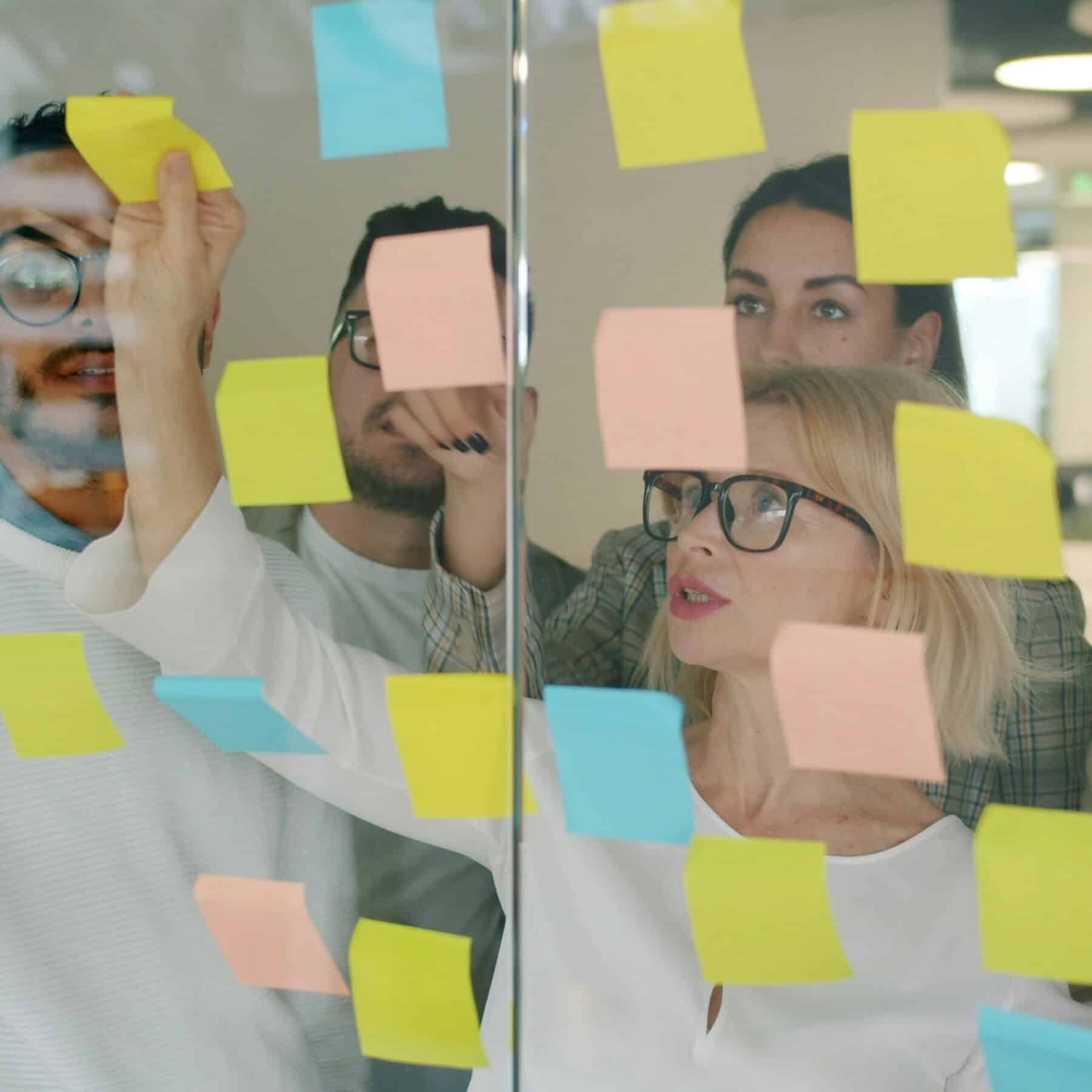 hr team reviewing glass board with post its on it