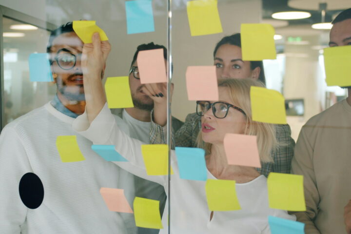 hr team reviewing glass board with post its on it