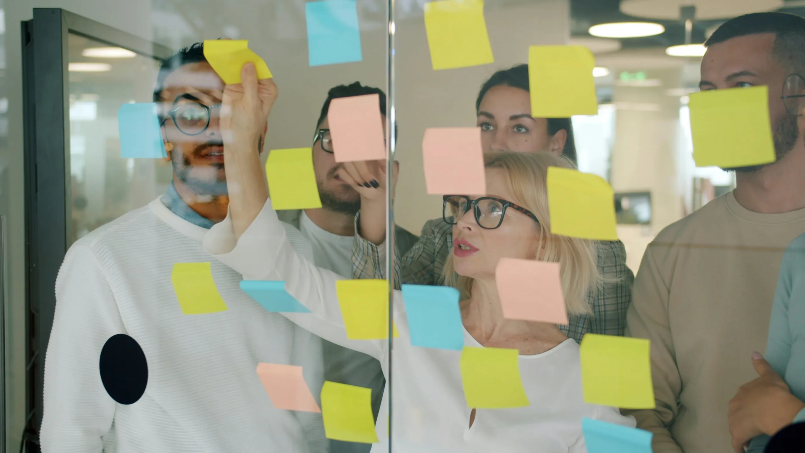 hr team reviewing glass board with post its on it