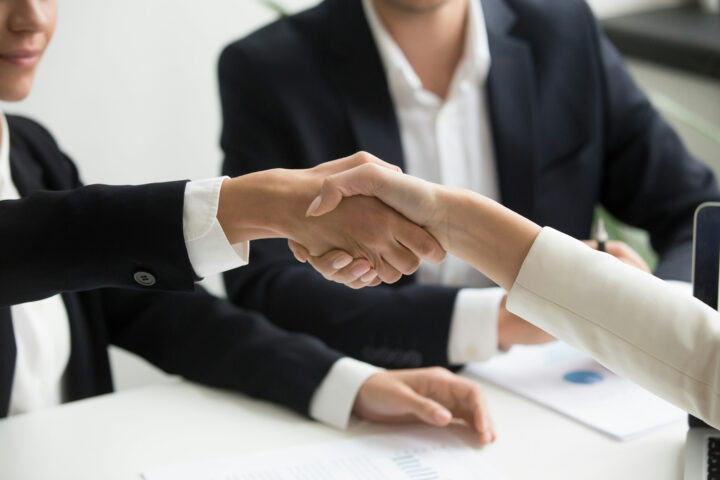 two business people shaking hands over the table