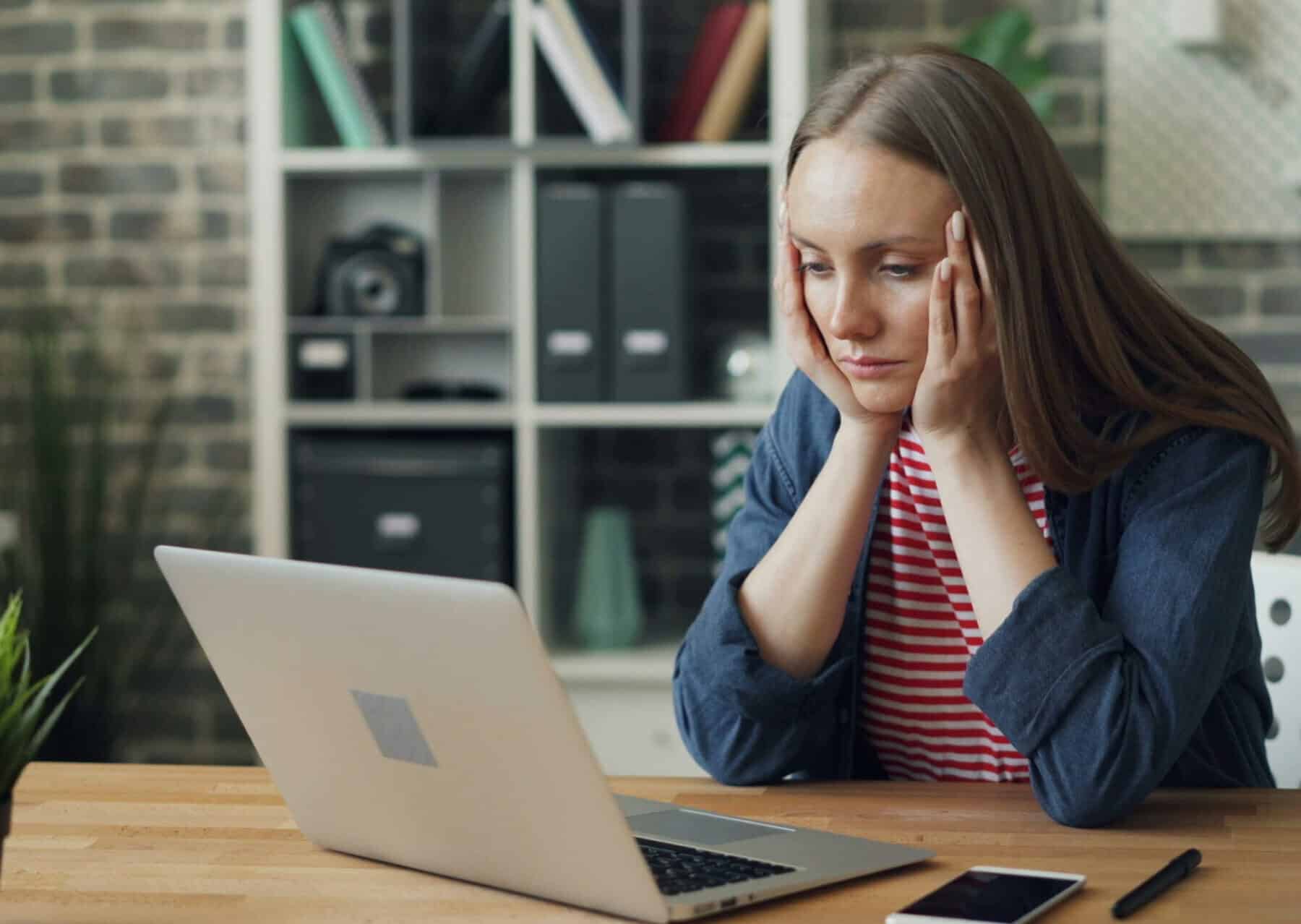 burnt out employee looking at computer with head in hands