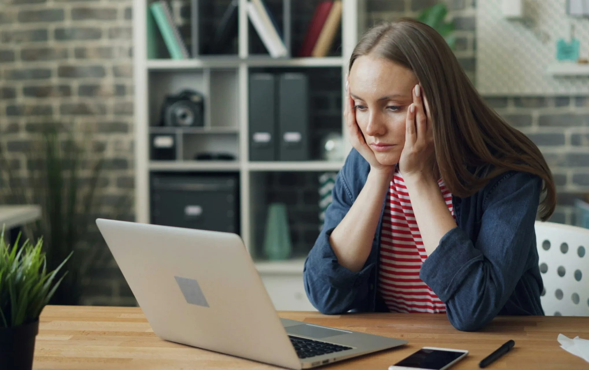 burnt out employee looking at computer with head in hands